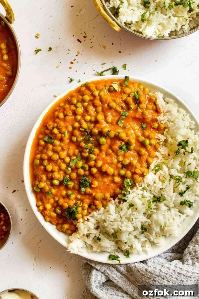 Quick and Flavorful Pea Curry Recipe for Weeknight Meals 4 Top down view of a white plate with rice and peas in orange sauce and green herbs sprinkled over.