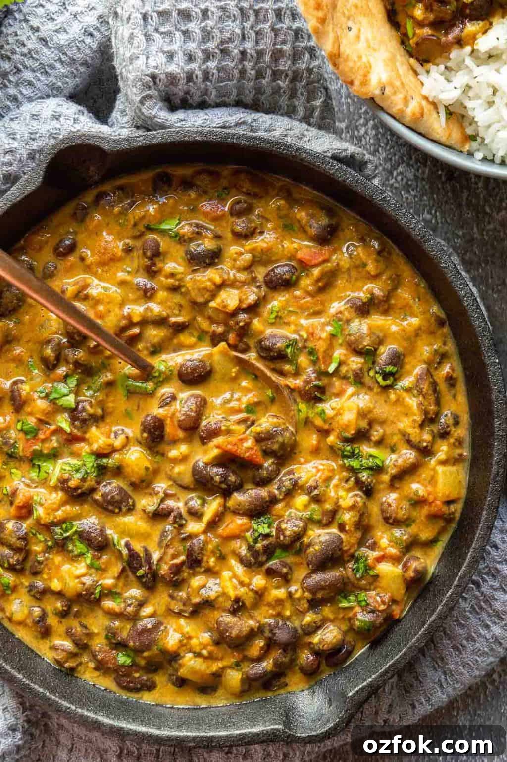 Quick and Flavorful Pea Curry Recipe for Weeknight Meals 7 Top down view of a black cast-iron pan with a creamy light brown bean curry, on a grey background.