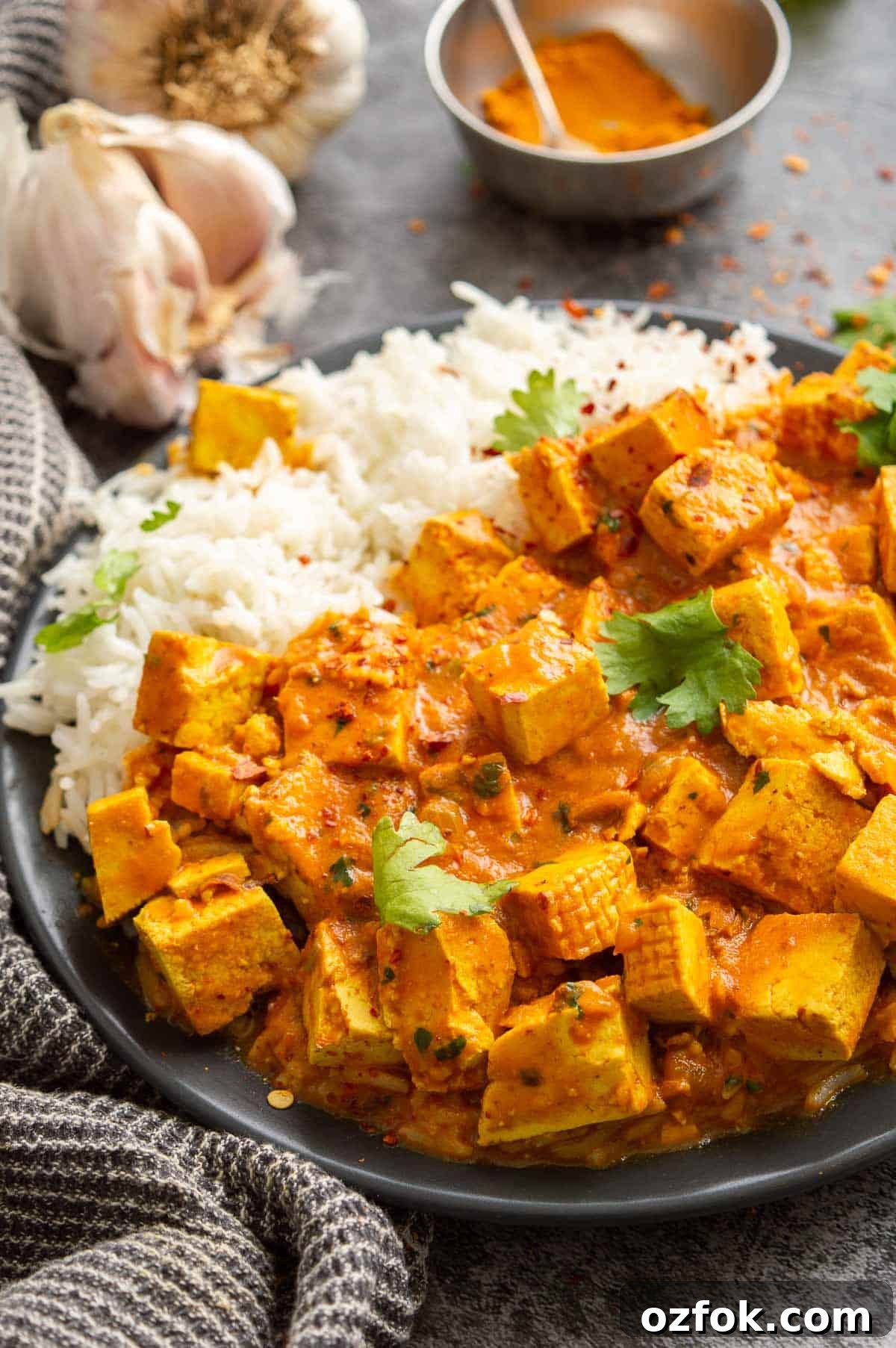 Quick and Flavorful Pea Curry Recipe for Weeknight Meals 8 Close-up of a black plate with rice and a yellow-orange creamy tofu curry.
