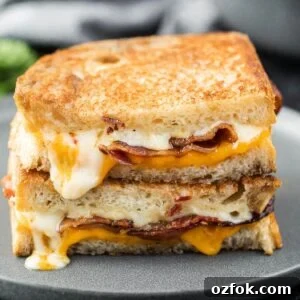 Grilled Cheese with bacon cut in half and stacked on a plate.