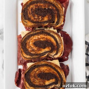 Three Reuben sandwiches stacked vertically on a plate