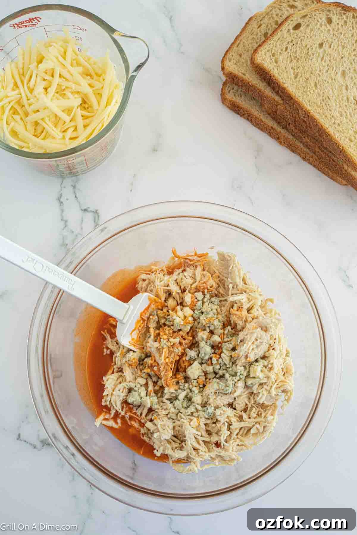 Mixing in shredded chicken and blue cheese crumbles in a bowl with the buffalo sauce mixture