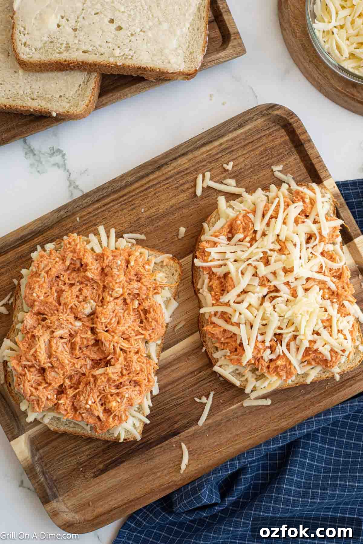 Topping slice of bread with shredded cheese and buffalo chicken