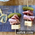 2 Cuban sandwich appetizers on a wood board.