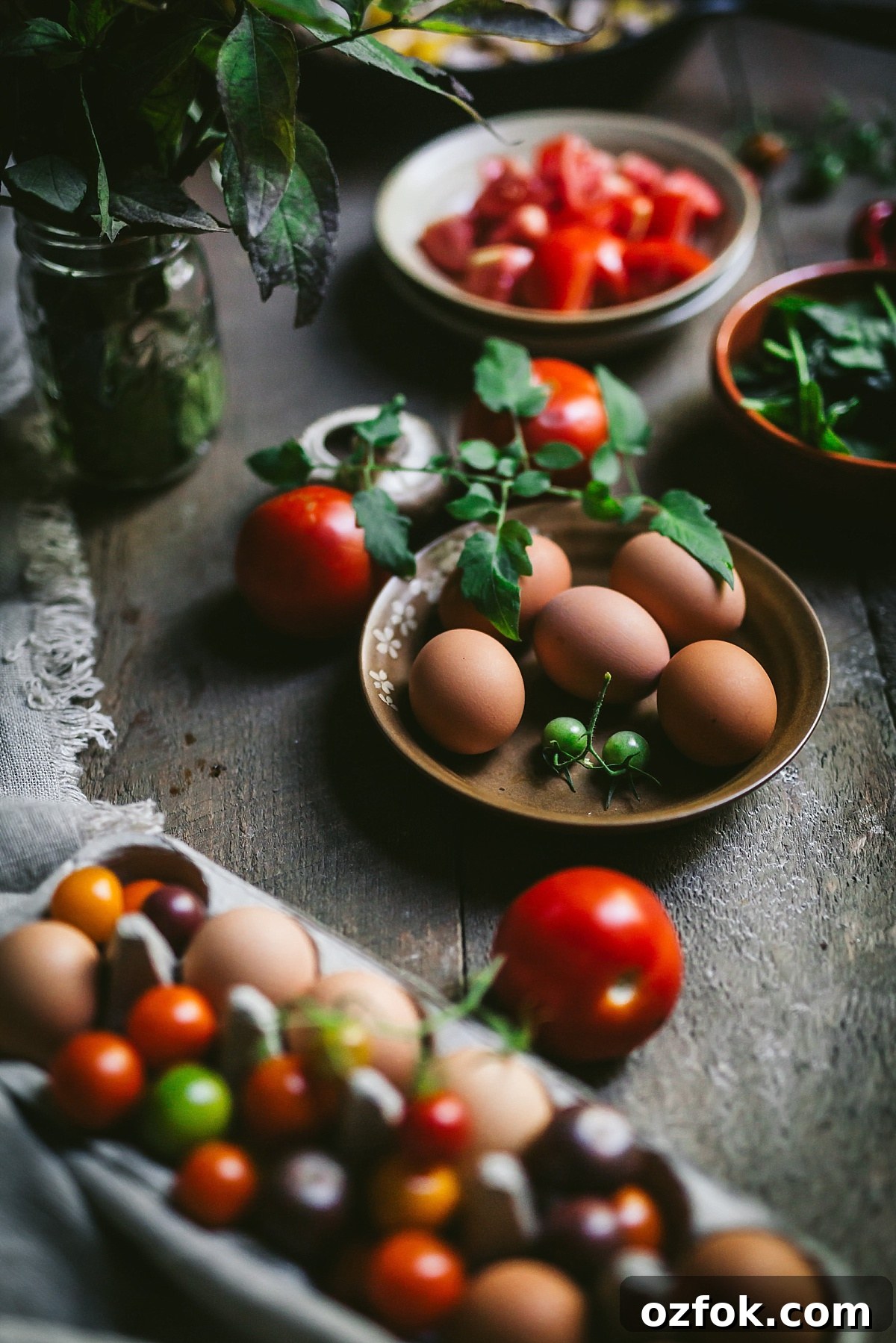 focus on plateful of fresh brown farm eggs surrounded by pretty tomatoes, large and small of many colors