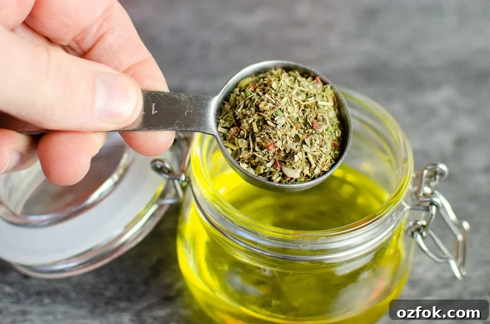 A tablespoon of Italian Herbs being poured into a pot with olive oil to make our Mediterranean salad dressing