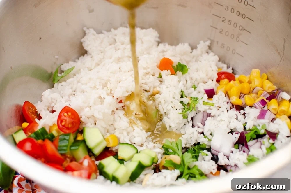Italian style rice salad being mixed all together in a large silver bowl