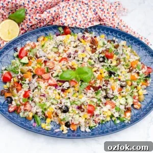 Italian Style Rice Salad on a large blue platter plate with lemon and basil on the side