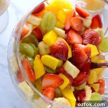A big bowl of fruit salad with a spoon.
