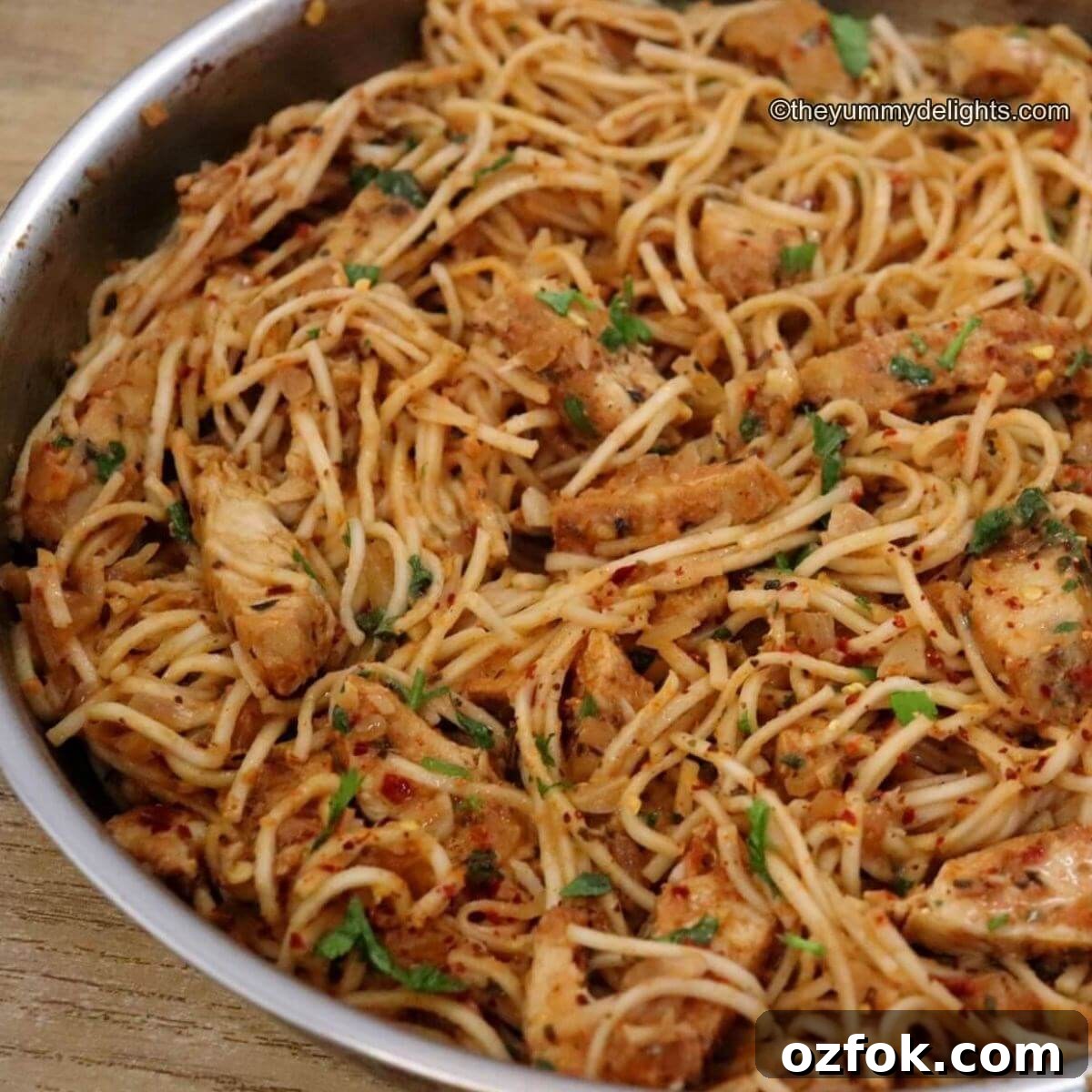 spicy chicken spaghetti in a skillet. This spicy chicken pasta is garnished with Parmesan cheese, parsley and a dash of red pepper flakes.