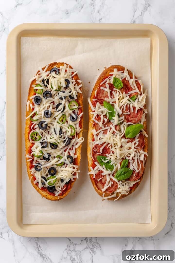 Two unbaked French bread pizzas on sheet pan