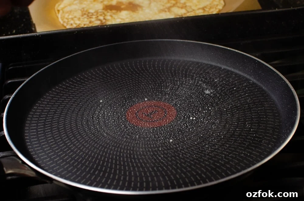 Spraying oil onto a pancake frying pan to cook our Easy English Pancakes