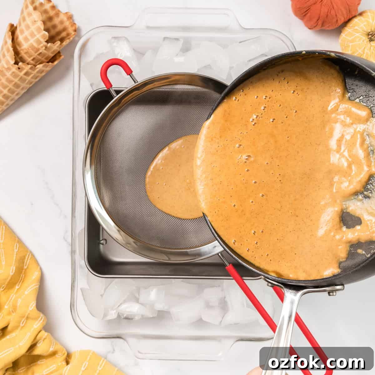 A pot pouring ice cream base through a strainer.