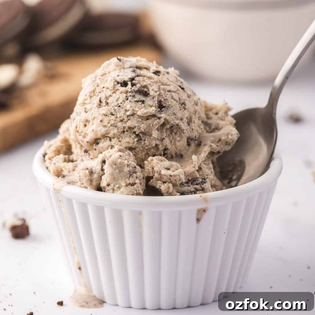 A scoop of cookies and cream ice cream in a white dish with a spoon.