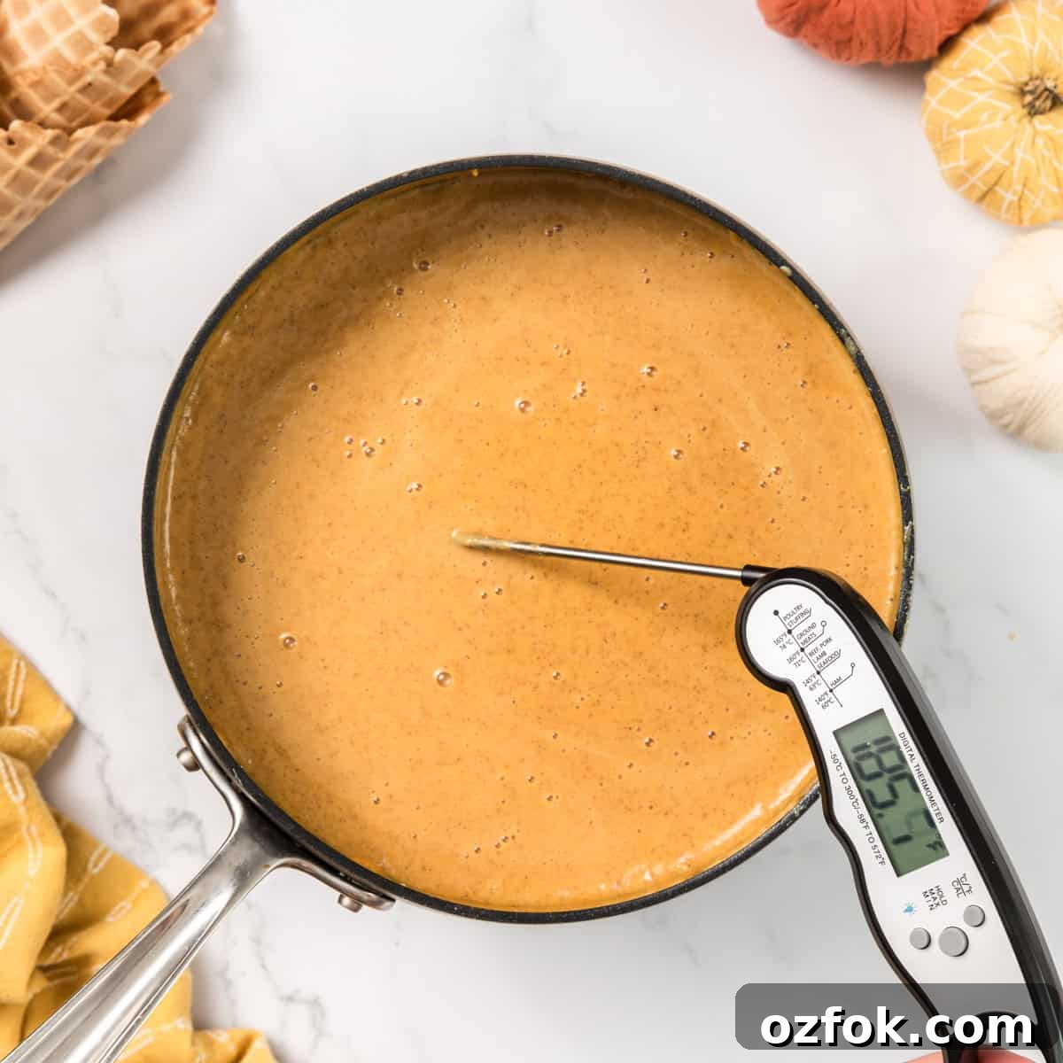 A thermometer taking the temperature of cream in a pot.