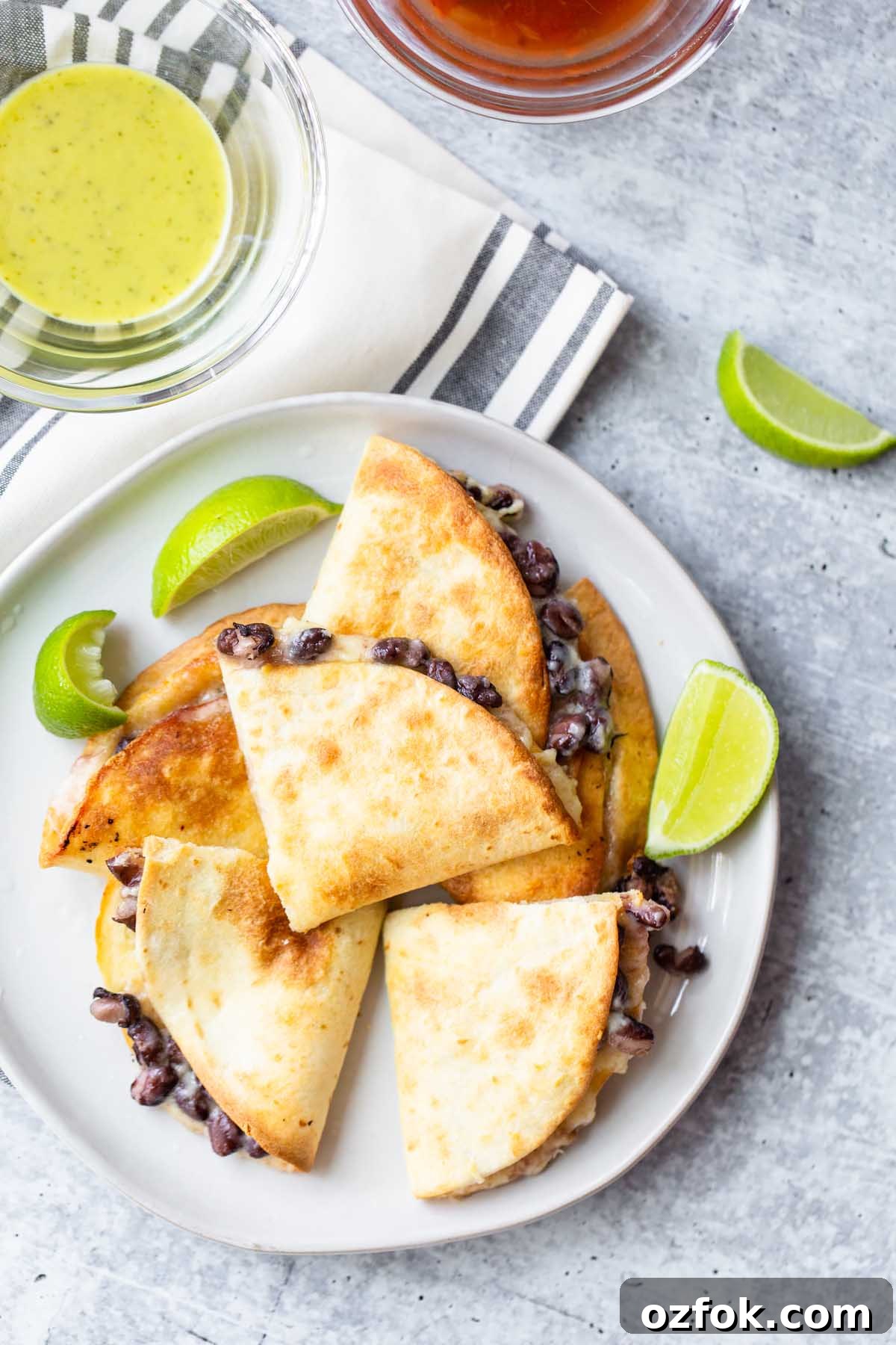 quesadillas on a plate with lime wedges and salsas on the side